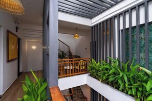 A modern interior with a wooden staircase, a hanging light fixture, and a plant-lined wall.