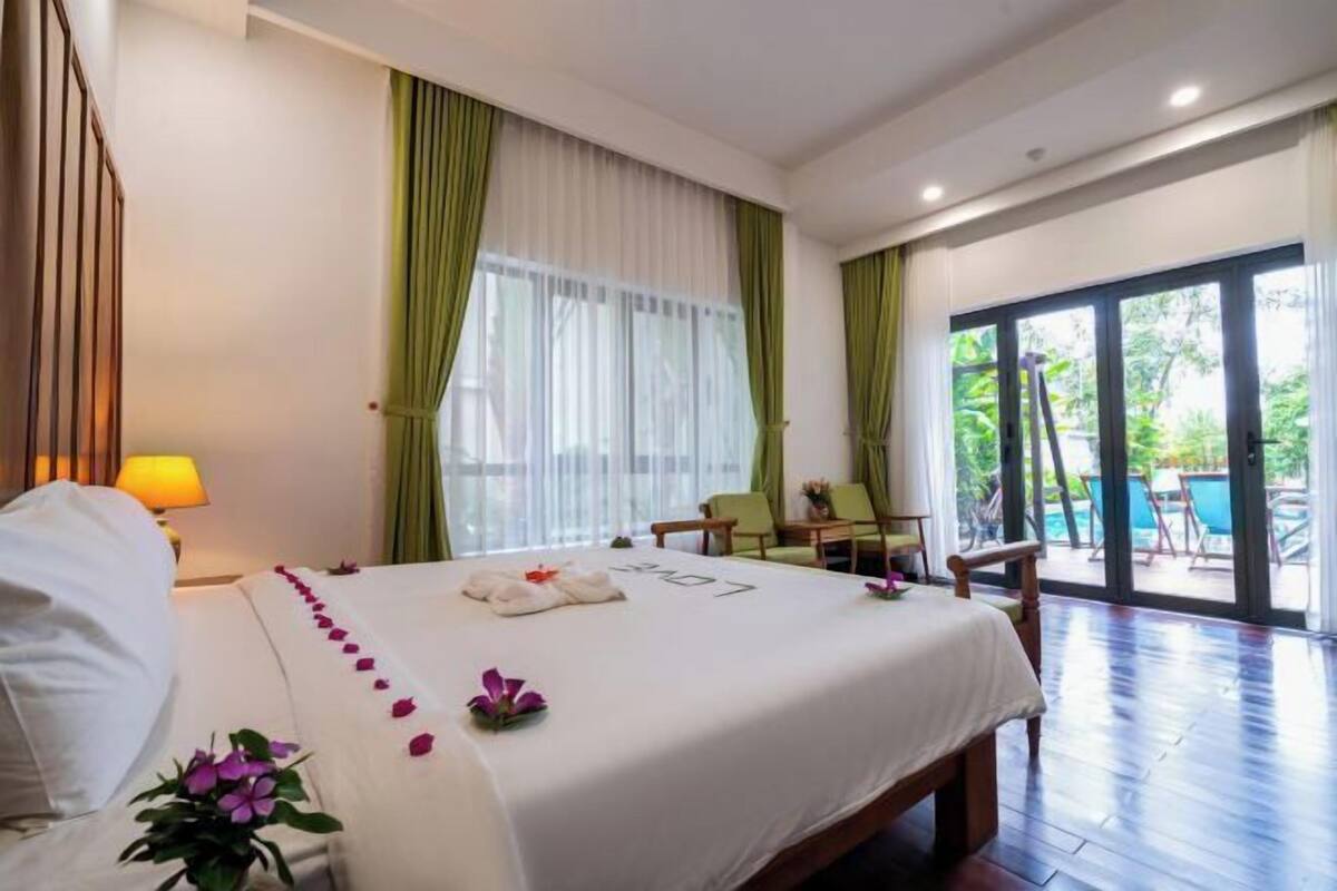 Ein Hotelzimmer mit Bett, Stuhl, Tisch und Blick ins Freie.