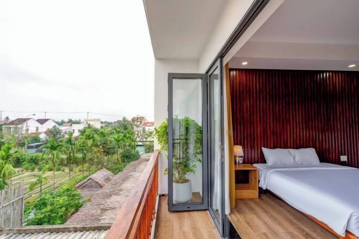 Ein modernes Schlafzimmer mit einer großen Schiebeglasdoor zu einem Balkon mit Blick auf eine Wohngegend.