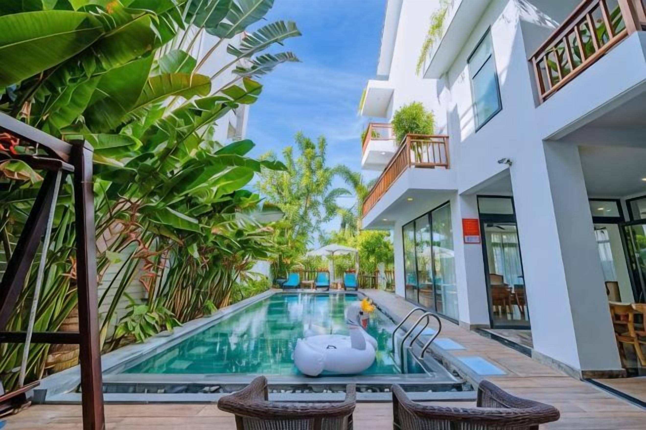 An indoor swimming pool with a swan float, surrounded by lush greenery and modern architecture.