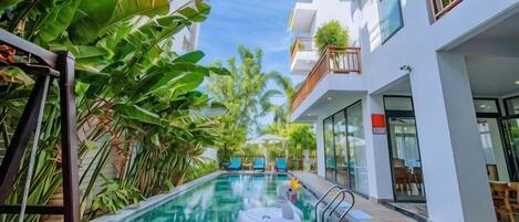 An indoor swimming pool with a swan float, surrounded by lush greenery and modern architecture.