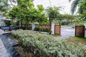 Een tuin met een houten omheining, een geplaveid pad en een bank.