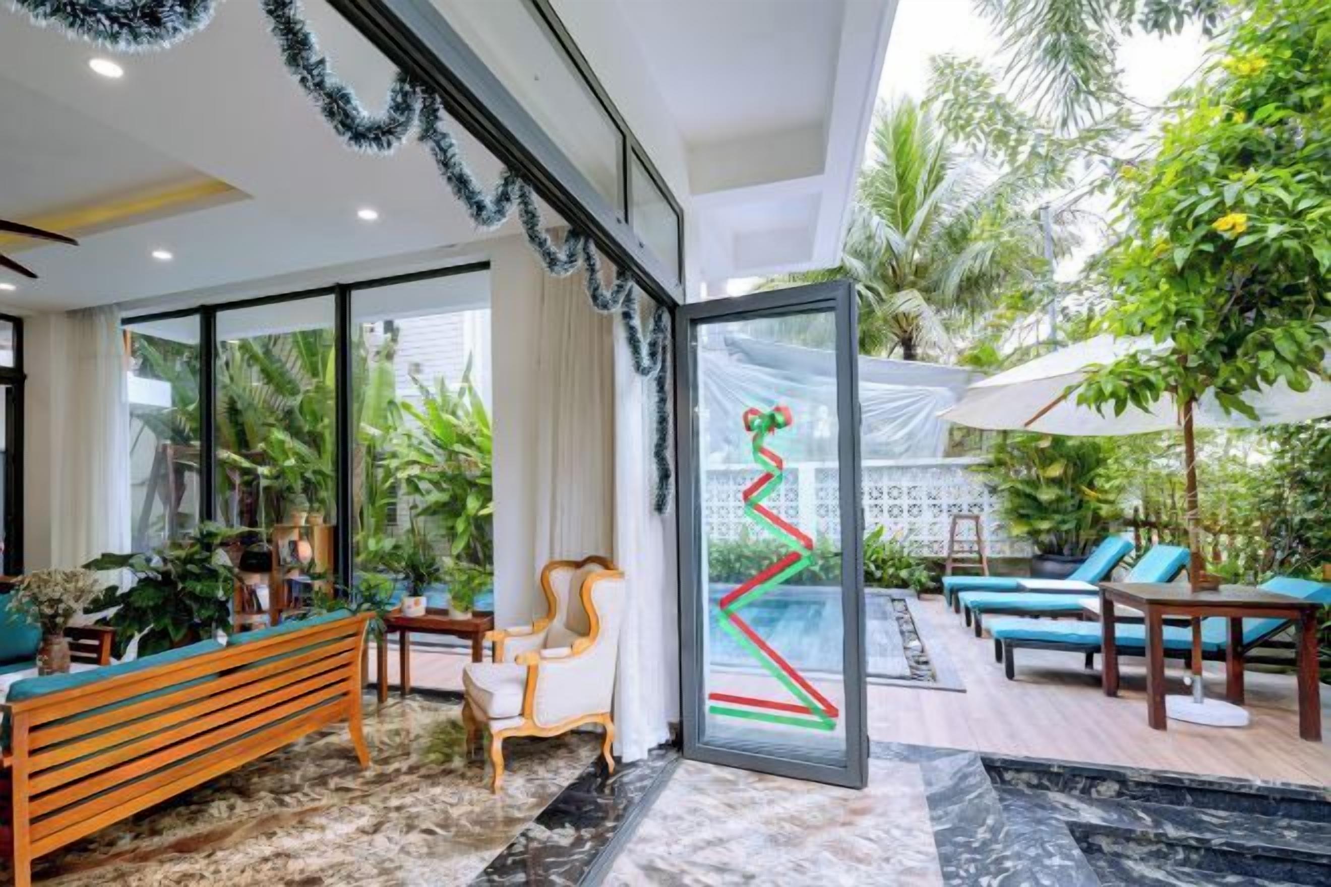 A modern interior with a glass door leading to a pool area, furnished with a bench, chairs, and a table.