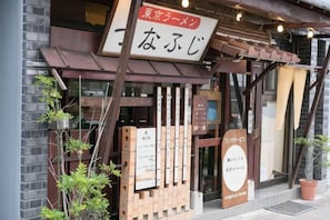 A restaurant with a wooden facade, signage in Japanese, and a small potted plant outside. - Maison de Takinogawa (Tokyo)