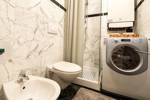 Un bagno con lavandino, WC e lavatrice.