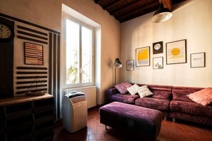 A living room with a sofa, a radiator, a window, and framed pictures on the wall. - Designer Apartments in Florence (Florence)
