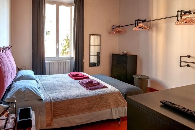 A bedroom with a bed, bedside table, dresser, and a window with curtains.