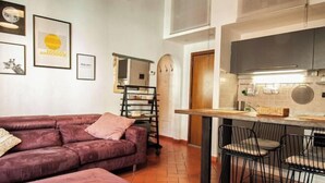A compact living space with a sofa, a small kitchen area, and a dining table with chairs. - Designer Apartments in Florence (Florence)