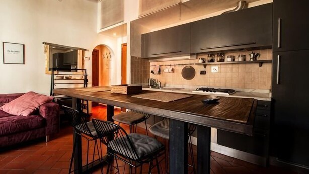 A modern kitchen with a central island, bar stools, and a dining table. - Designer Apartments in Florence (Florence)