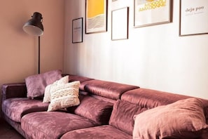 A room with a pink sofa, a floor lamp, and framed artwork on the wall. - Designer Apartments in Florence (Florence)