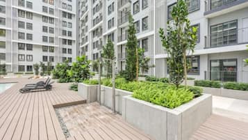 Un immeuble résidentiel moderne doté de nombreux balcons, d’une terrasse sur le toit et d’espaces verts aménagés.