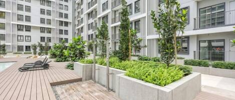 Un edificio residencial moderno con varios balcones, una terraza en la azotea y zonas ajardinadas.