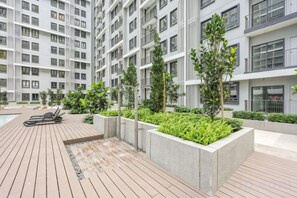 Un edificio residencial moderno con varios balcones, una terraza en la azotea y zonas ajardinadas.