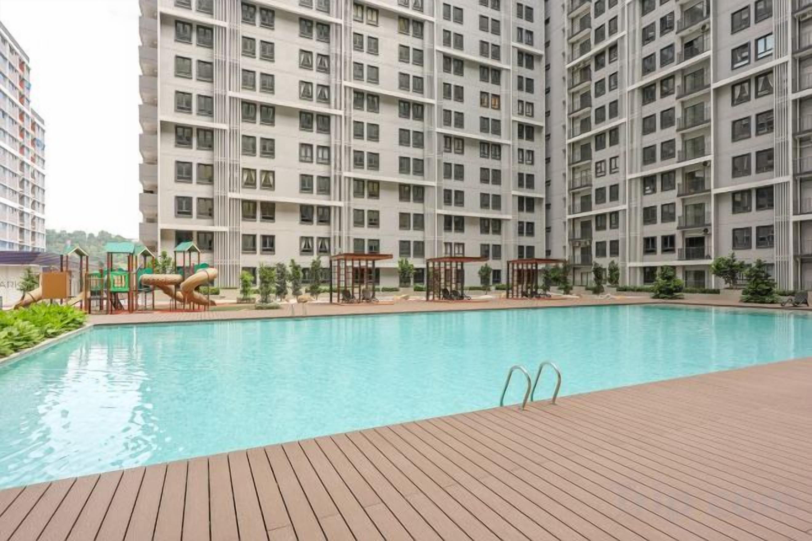 A swimming pool with a wooden deck, surrounded by high-rise residential buildings.