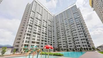 A high-rise residential building with a swimming pool and outdoor play area.