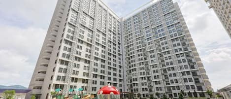 A high-rise residential building with a swimming pool and outdoor play area.