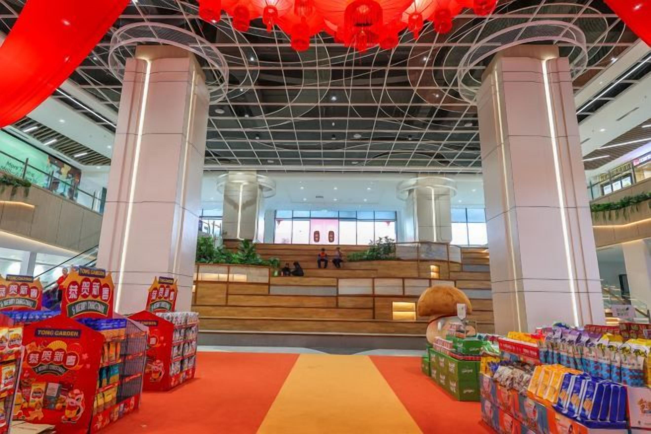 A spacious indoor area with a central seating area, surrounded by various food and beverage displays.