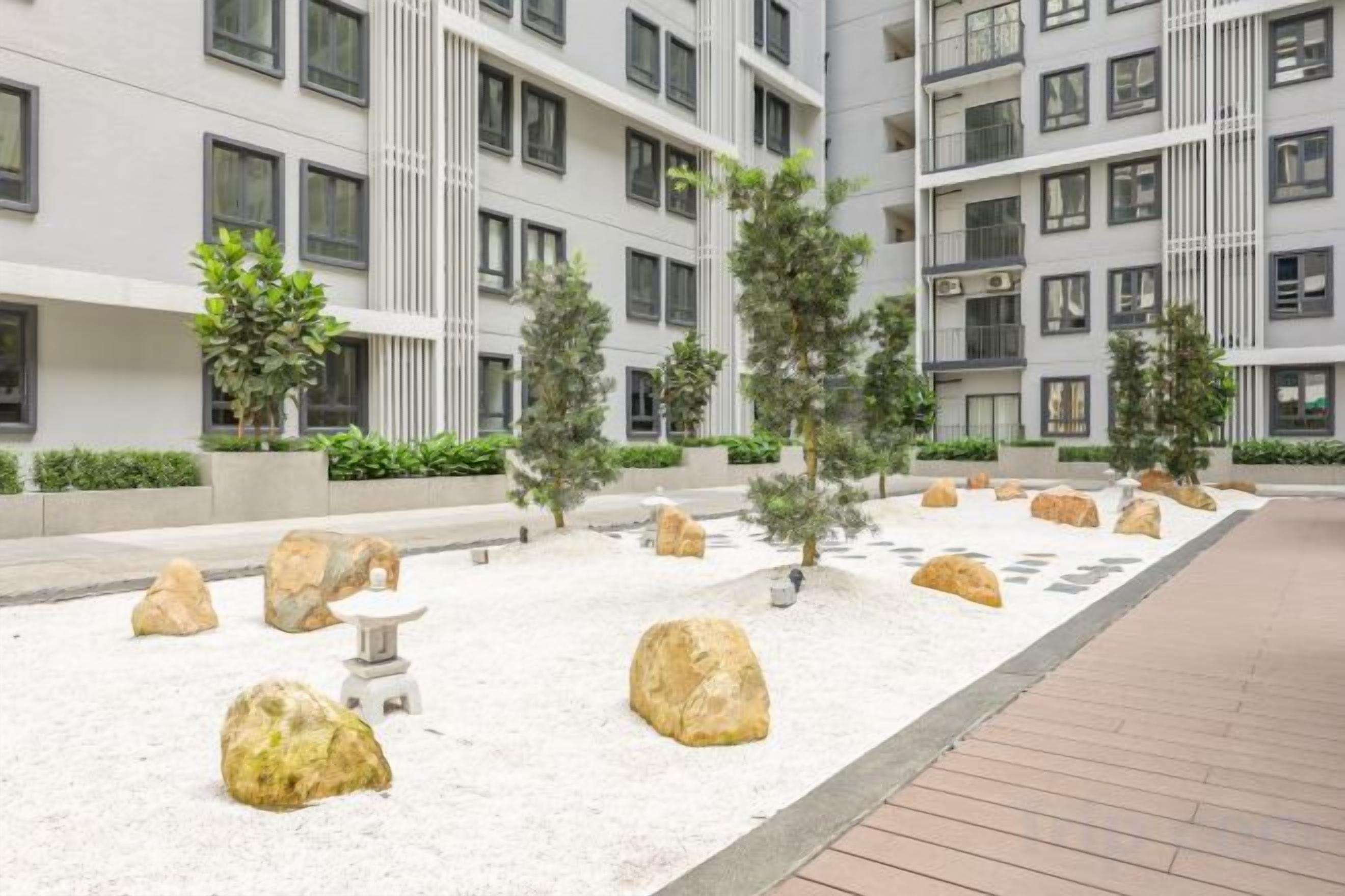 A courtyard with a white floor, large rocks, and a few trees.
