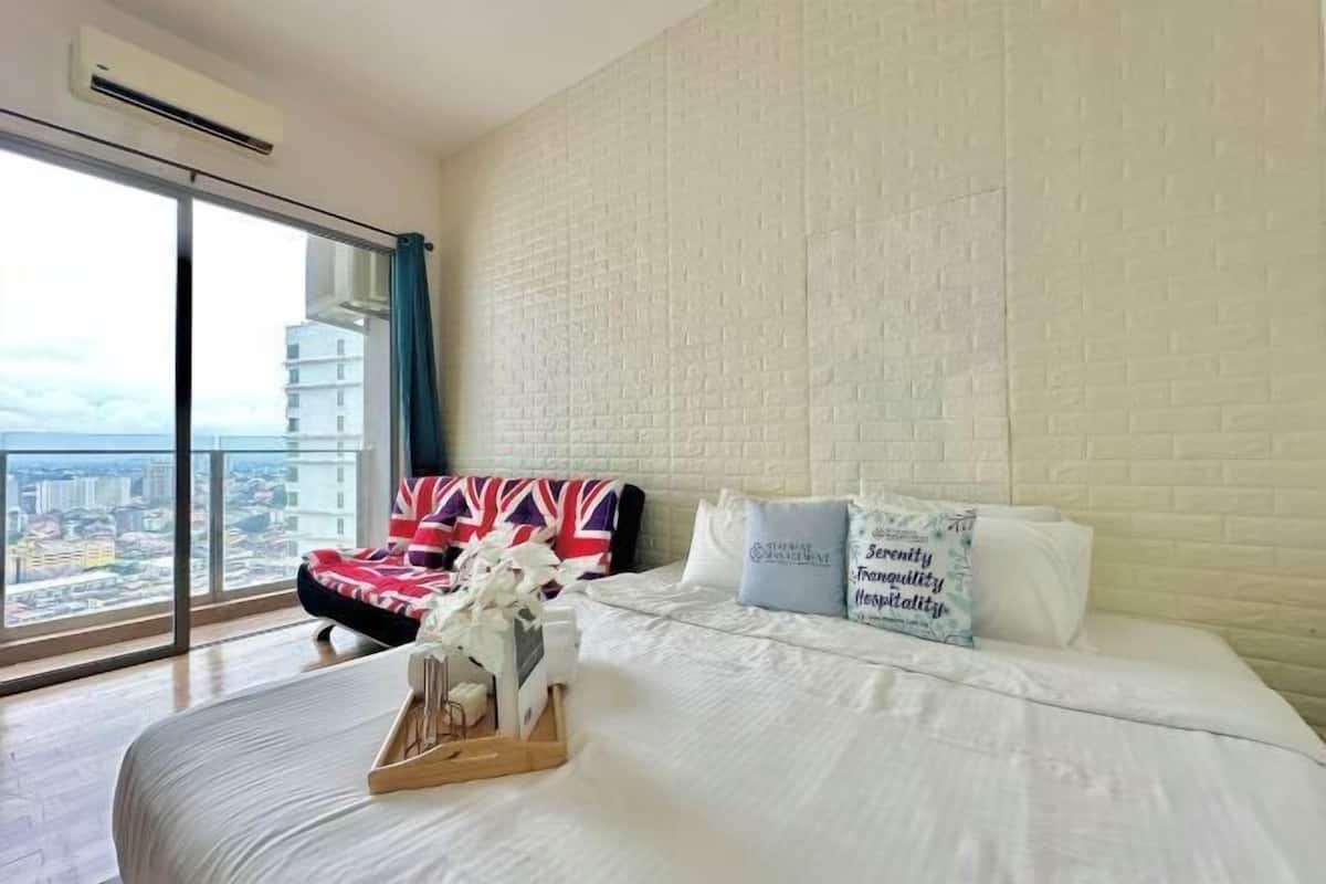 Habitación de hotel con una cama grande, vistas a la ciudad y una pared de ladrillo.