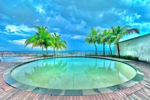 Una piscina a sfioro circolare con vista sull'oceano e palme.