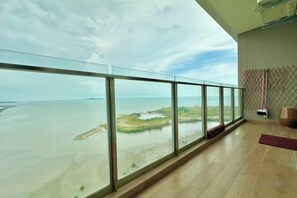 Une pièce dotée d’un grand balcon en verre donnant sur une rivière et un paysage lointain.