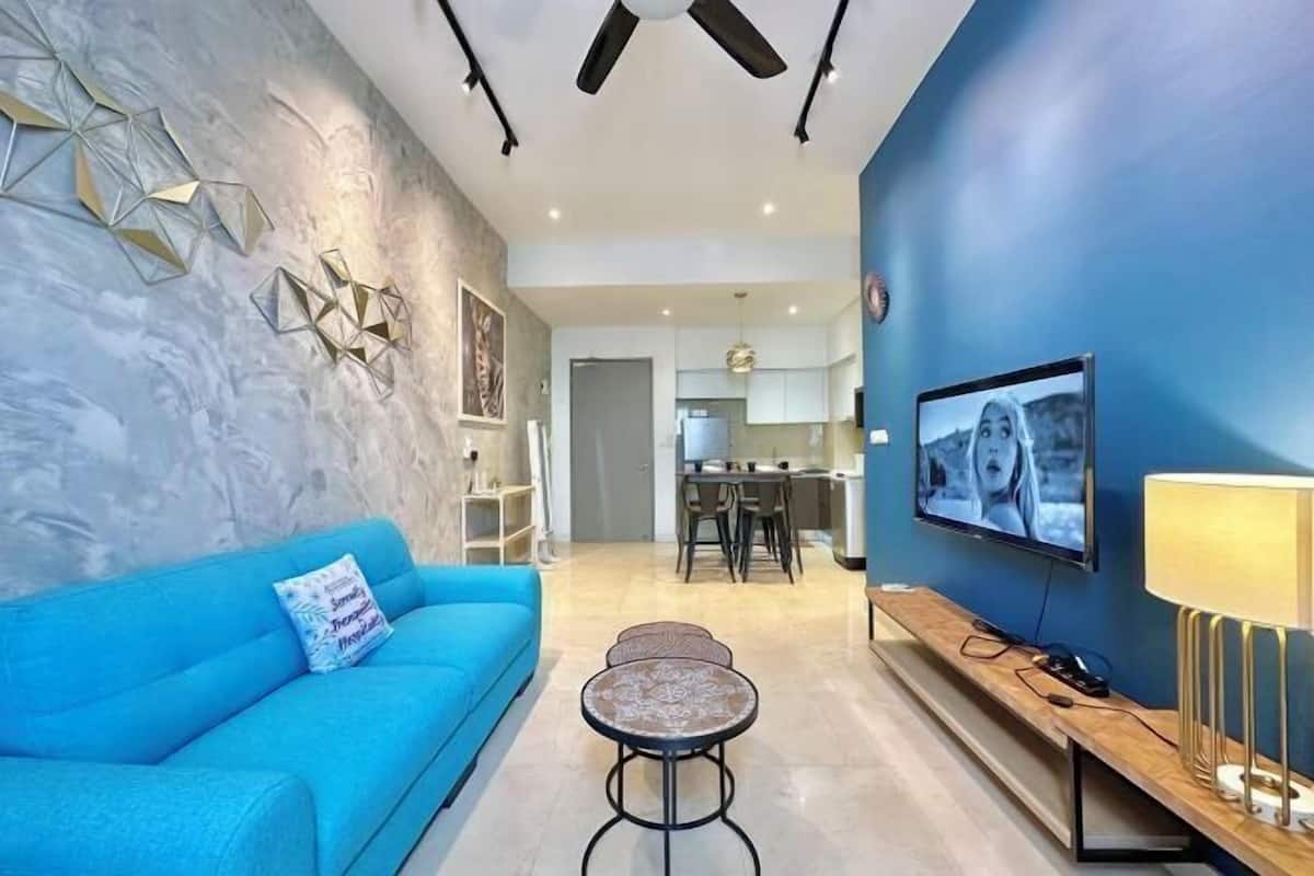 Una sala de estar moderna con un sofá azul, una mesa de centro y un televisor sobre un mueble de madera.