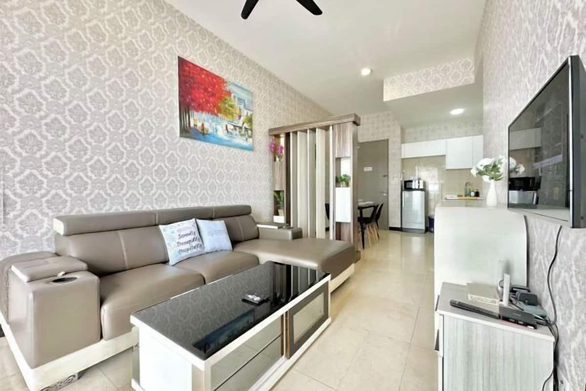 Una sala de estar moderna con un sofá, una mesa de centro y una zona de cocina al fondo.