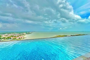 A swimming pool with a view of a coastal area and a distant shoreline.