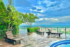 Eine Holzterrasse mit zwei Liegestühlen und einem Poolbereich.