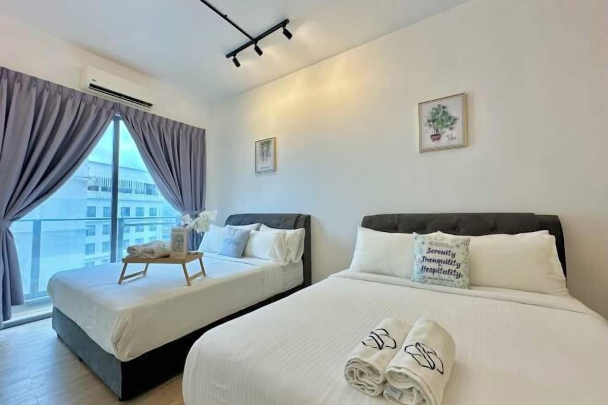 Habitación de hotel con dos camas, un ventanal grande y vista a edificios.
