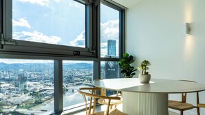 A modern dining area with a panoramic city view, a round table, and wicker chairs.