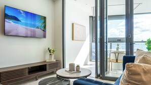 A modern living room with a TV, sofa, coffee table, and a balcony with a city view.