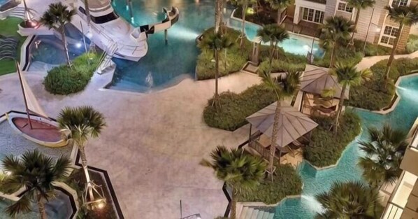 Oversigtsbillede af et resort med en central swimmingpool, palmer og en pavillon.