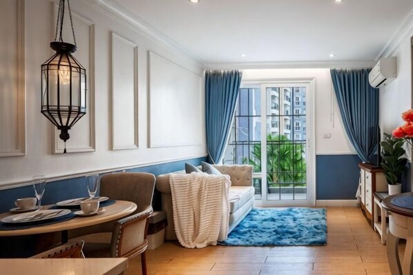 A room with a dining table, chairs, a sofa, a blue rug, and a view through a glass door. - Seven Seas Cote d'Azur One-bedroom near Beach (Pattaya)