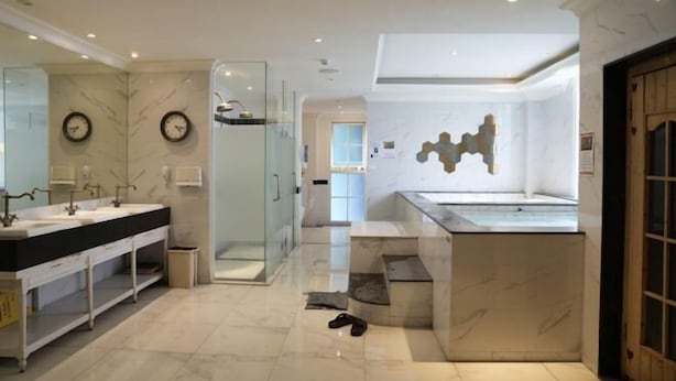 A modern bathroom with dual sinks, a glass shower enclosure, and a marble floor.