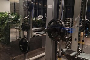 A gym with weightlifting equipment, a bench, and a mirror reflecting the interior. - Pavillion Bukit Jalil 【Walk 5 mins】Stylish Studio 2-4 Pax (Kuala Lumpur)