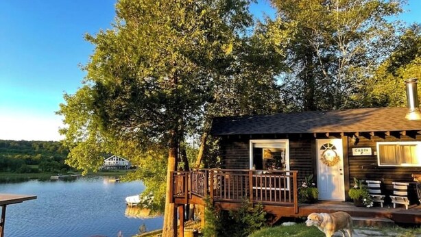 Une cabane au bord d’un lac, dotée d’une terrasse et de meubles d’extérieur.