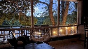 Une pièce chaleureuse avec une grande fenêtre donnant sur un lac, une table en bois et des chaises en osier.
