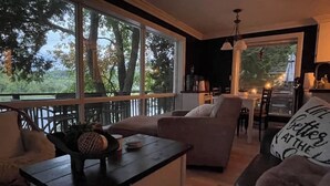 Un salon confortable avec une grande fenêtre, un coin repas et une cuisine.