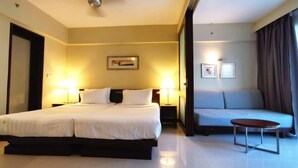A hotel room with a double bed, a sofa, a small table, and two wall-mounted lamps. - PD Admiral Cove Private Unit - Up to 4 Pax (Port Dickson)