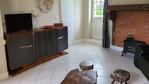 A living room with a television on a wooden cabinet, a fireplace, and a door leading outside.