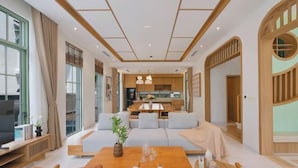A modern living room with a sofa, coffee table, and a dining area.