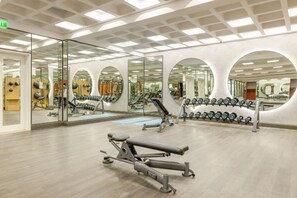 Una palestra con pareti a specchio, attrezzature per esercizi e pavimento in legno.