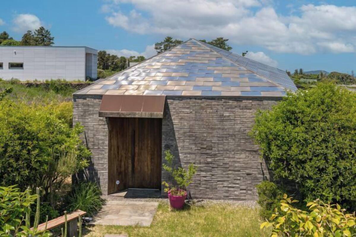 Ein kleines Steinhaus mit schrägem Dach, einer Holztür und einem Blumentopf im Vorbereich.