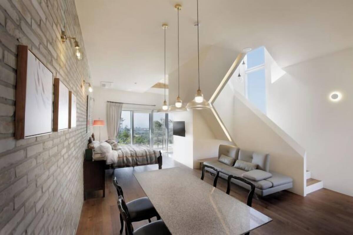 Ein modernes Wohnzimmer mit Essbereich, einer Treppe und großen Fenstern.