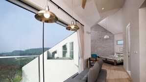 A modern bedroom with a large window, a sofa, and a bed. - Kairosjeju Boutique Stay (Jeju)