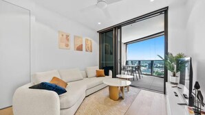 Un salon moderne avec un canapé blanc, une table basse et une vue sur la ville grâce à de grandes fenêtres.