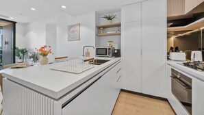 Une cuisine moderne avec des meubles blancs, un îlot central et des appareils électroménagers intégrés.