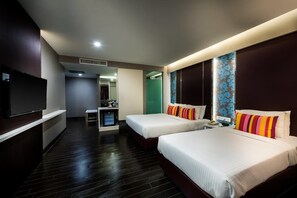 Ein Hotelzimmer mit zwei Betten, einem Fernseher, einem Schreibtisch und einem Spiegel.