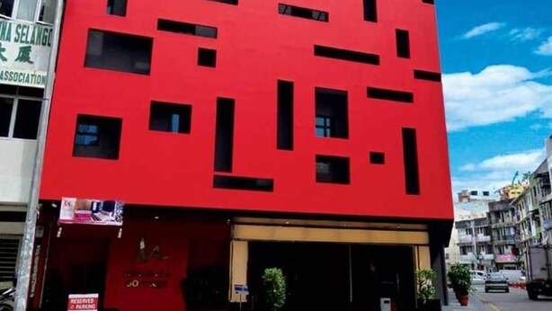 Een rood gebouw met veel ramen en een bord waarop staat aangegeven gereserveerd parkeren.
